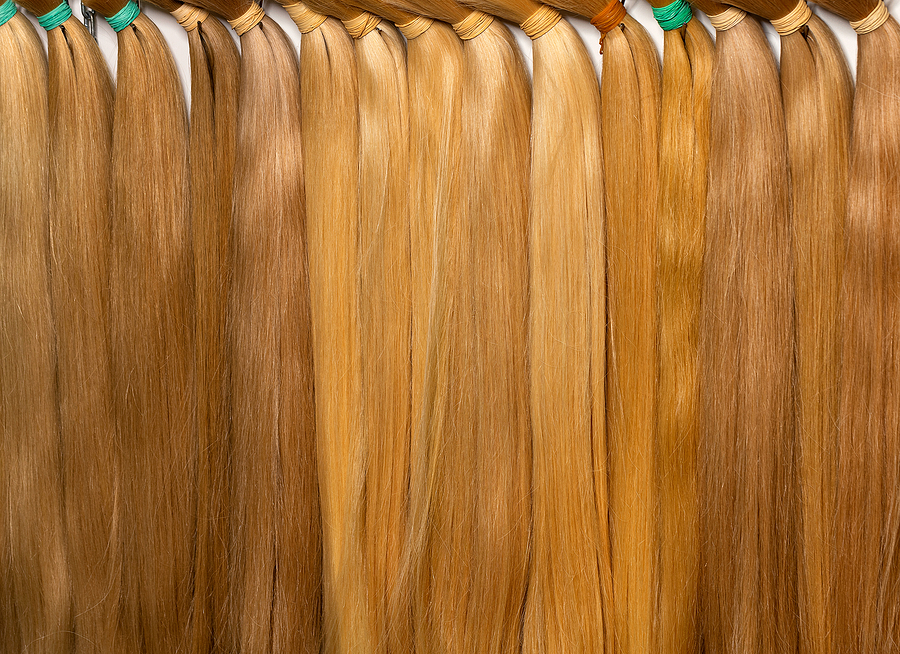 Natural straight human hair in light tones in bundles with various shades of straw color is used in the beauty industry for extensions.