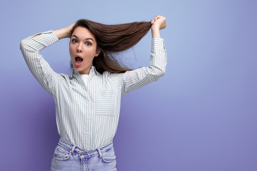 charming young brunette female adult with chic silky healthy hair below her shoulders in a studio background.